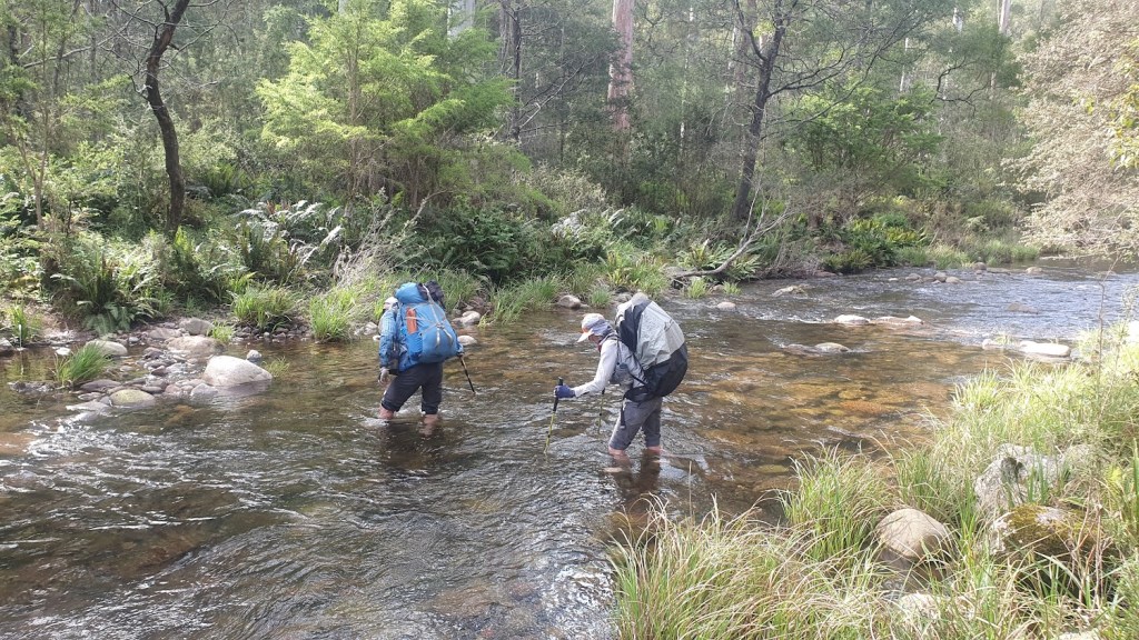 Two trekkers cross a stream