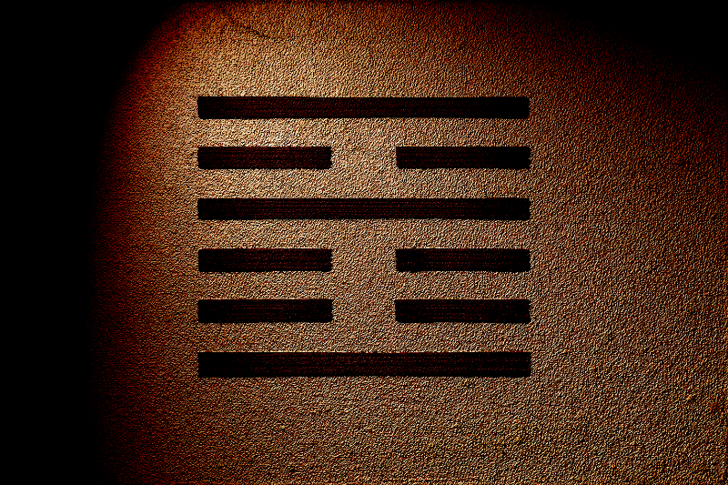 Black on gold image of the Yi Jing (I Ching) hexagram 21 Biting Through. Bottom to top, the lines are Yang (solid), Yin (broken), Yin, Yang, Yin, Yang.